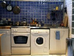 Blue Backsplash in kitchen with washing, microwave and dishwasher.