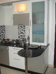 Black colored granite on L shaped Kitchen counter top with white colored cabinets Granite cladding