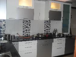 Black colored granite on Kitchen counter top with white colored cabinets Granite cladding