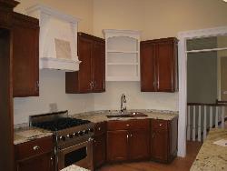 Wooden kitchen having stainless steel cooking range and wooden cover for hood  of wooden cupboards